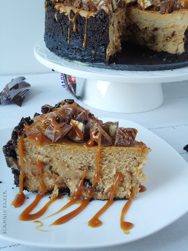 A creamy snickers peanut butter cheesecake recipe with a chocolate oreo crust and brown sugar salted caramel drizzle. Perfect for Halloween!