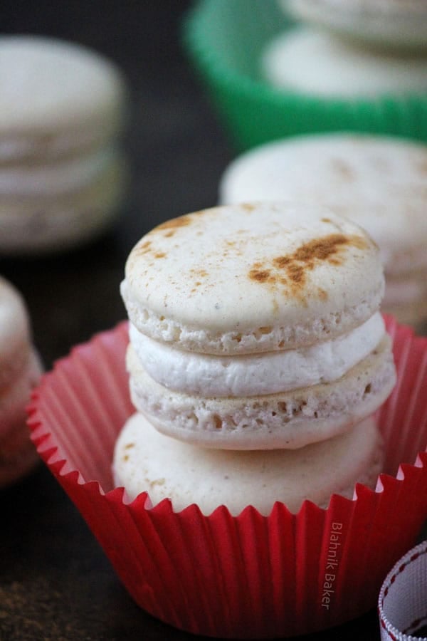 Eggnog macarons are perfectly spiced holiday cookies, with hints of cinnamon, cloves and nutmeg, filled with creamy eggnog buttercream. | Recipe on BlahnikBaker.com