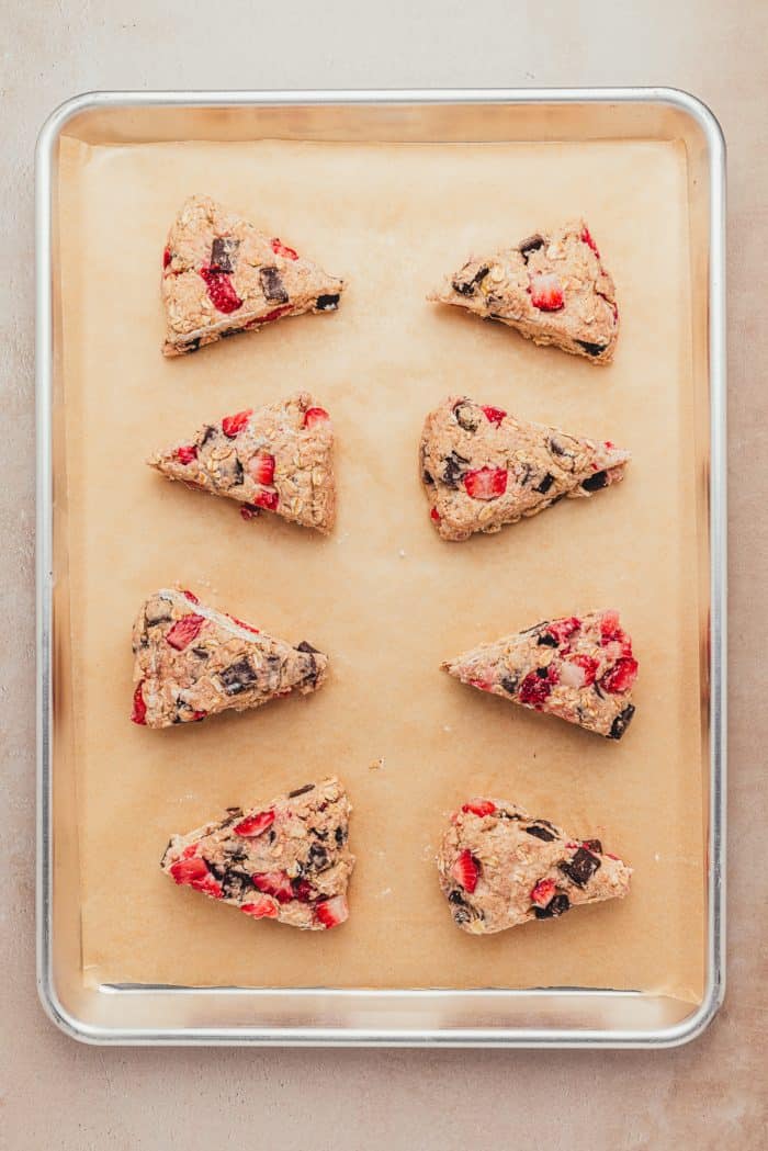 The unbaked scones on parchment paper on a baking sheet. 