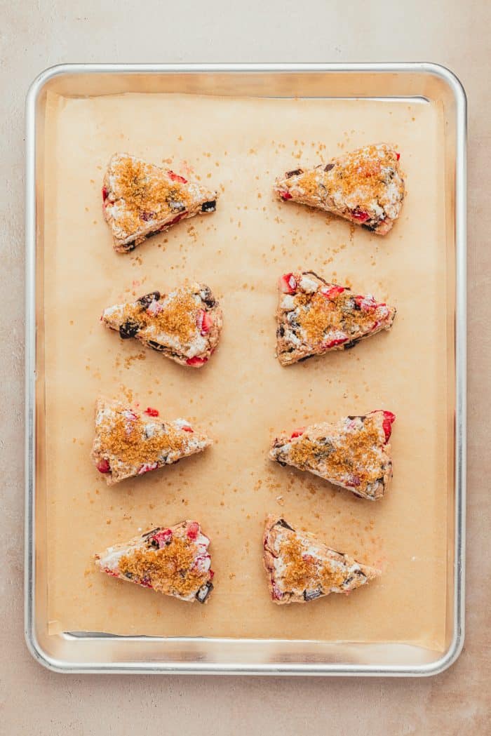 The unbaked scones on parchment paper on a baking sheet.