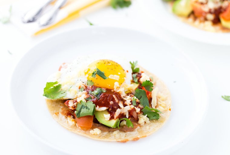 An authentic huevos rancheros recipe with homemade red chile paste, fried eggs and refried beans. 