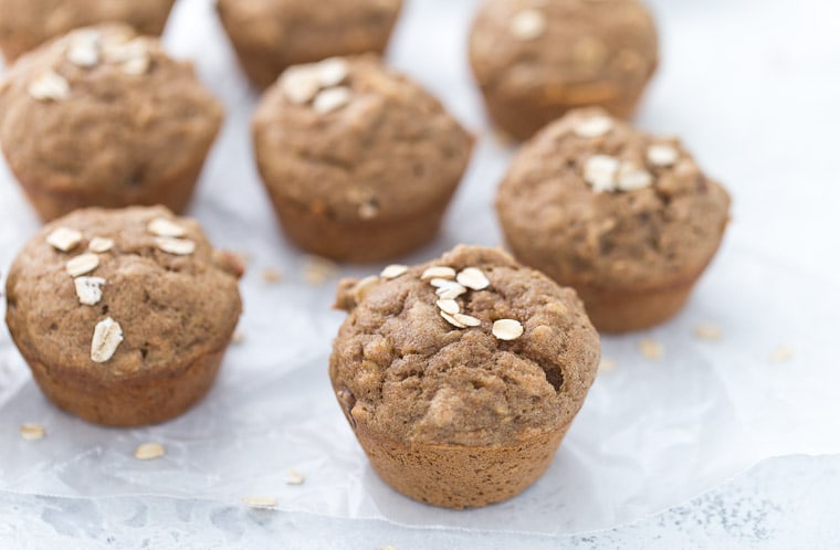 banana nut muffins on a white background with wax paper.