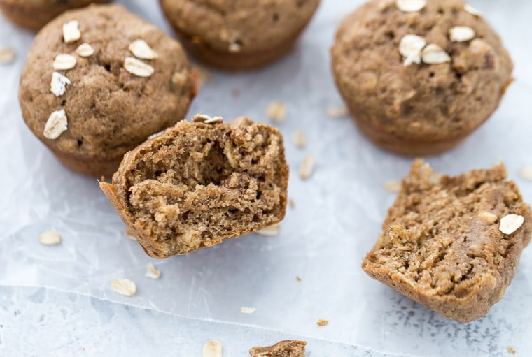 A banana nut muffin cut in half with various banana nut muffins in the background. 