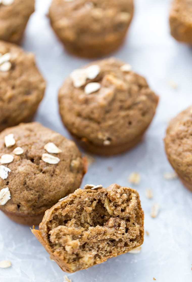 A banana nut muffin cut in half with various banana nut muffins in the background. 