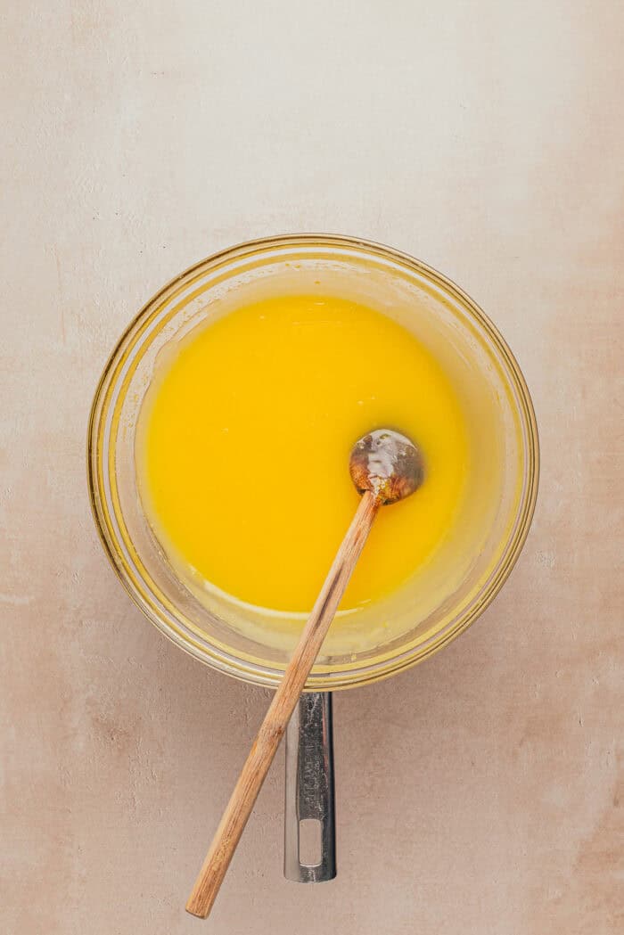 In a large bowl, a whisk is whisking the lemon custard filling.
