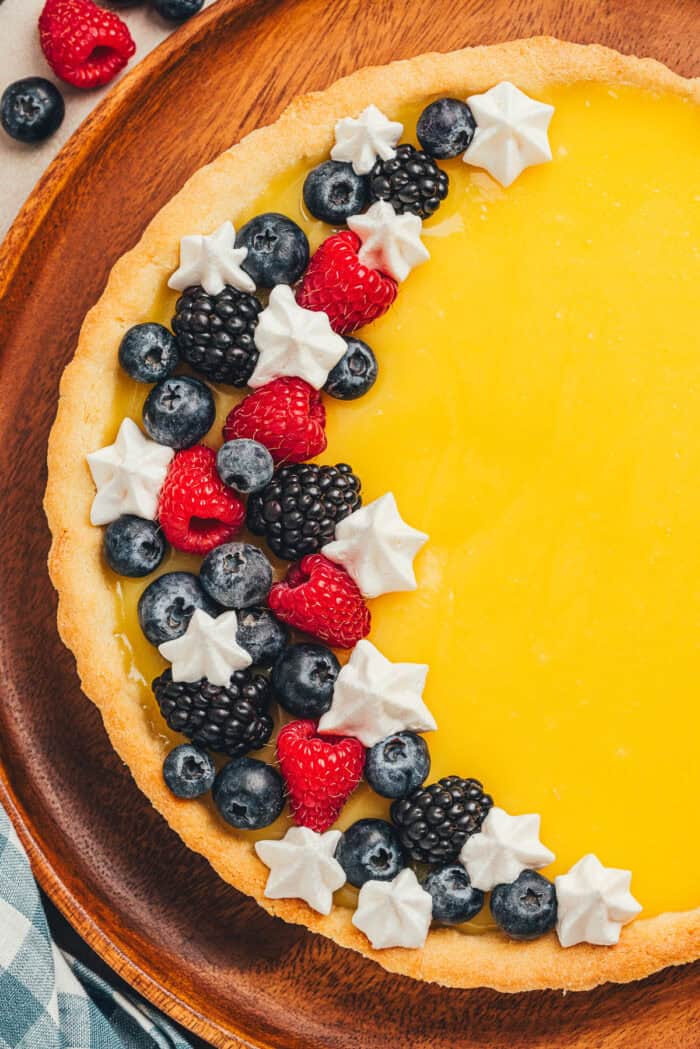 A homemade classic lemon tart on a tray, decorated with berries.