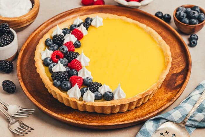A homemade classic lemon tart on a tray, decorated with berries.