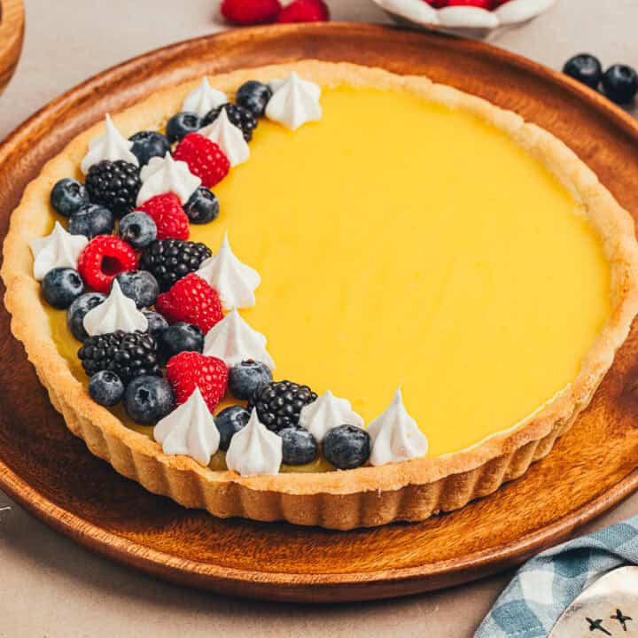 A homemade classic lemon tart on a tray, decorated with berries.