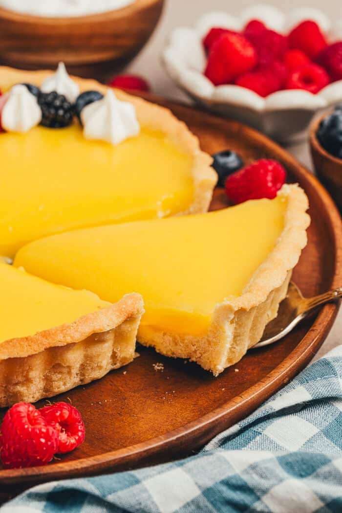 A slice of homemade lemon tart is being removed from the tart.