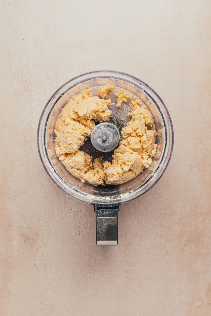 A food processor with the ingredients used to make a shortbread tart crust.