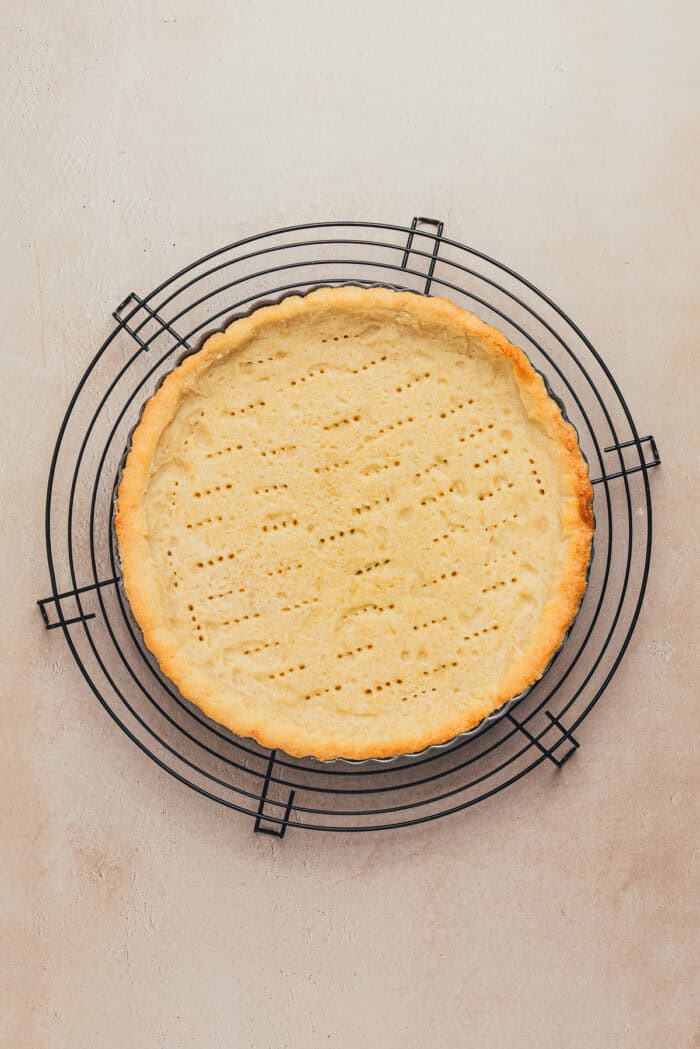 A baked shortbread tart crust on a cooling rack.