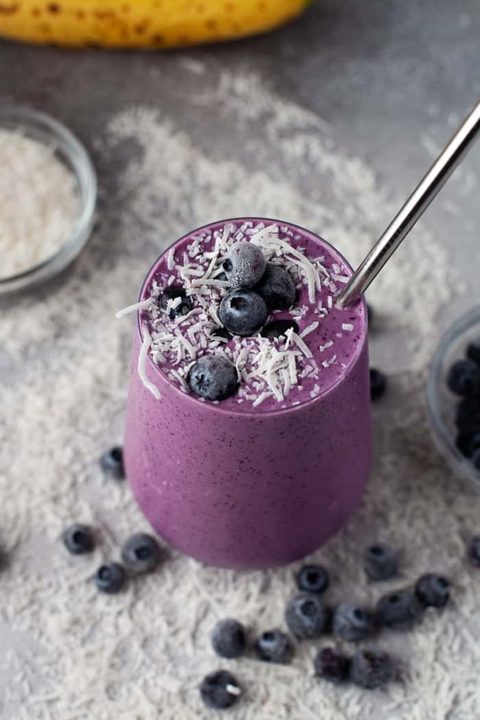Healthy Blueberry Smoothie with blueberries and coconut flakes around it. 
