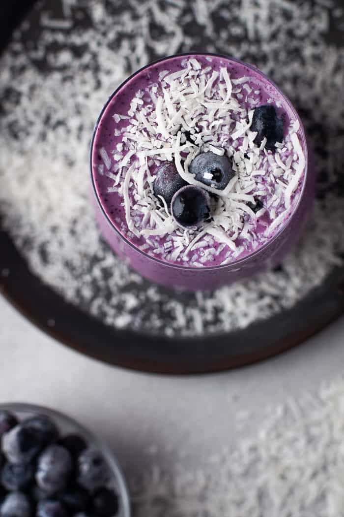 Healthy Blueberry Smoothie with coconut flakes around it. 