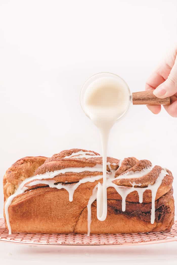 Cinnamon Swirl Bread with icing being drizzled all over it. 