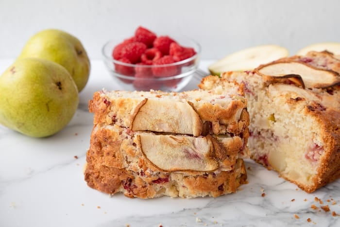Pear and Raspberry Bread sliced on a marble background. 