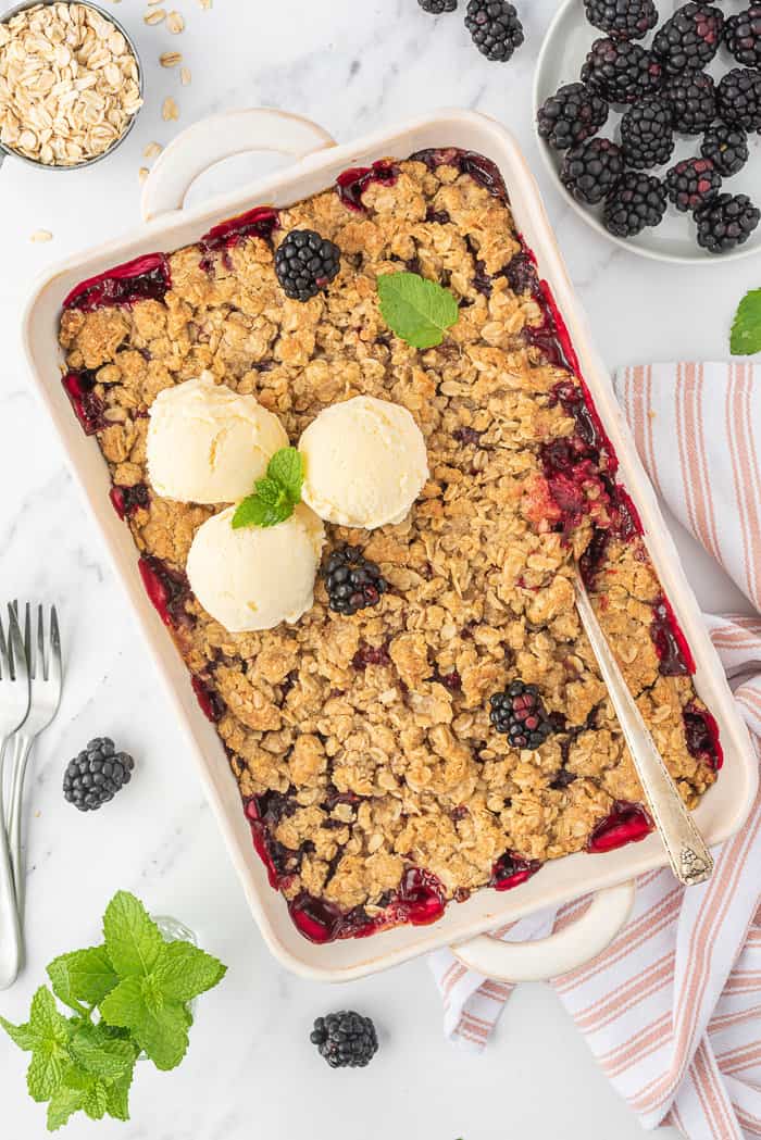 Blackberry crumble in a baking dish with ice cream.