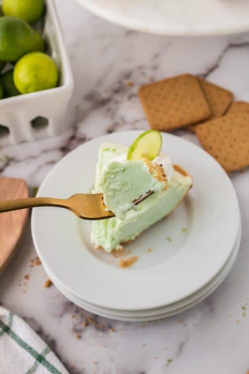 A slice of No Bake Key Lime Pieon a plate with a bite out of it.