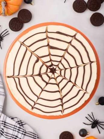 No-bake spider web cheesecake surrounded by Halloween decor.