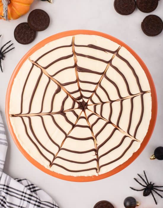 No-bake spider web cheesecake surrounded by Halloween decor.