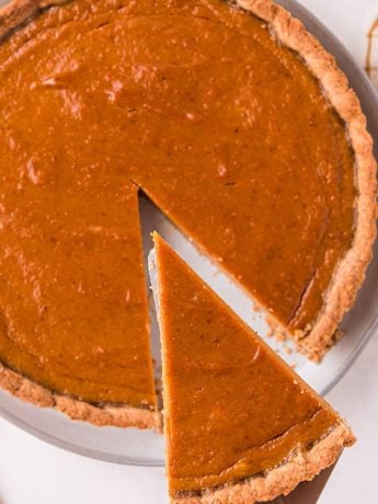 Pumpkin tart with a slice being taken out.
