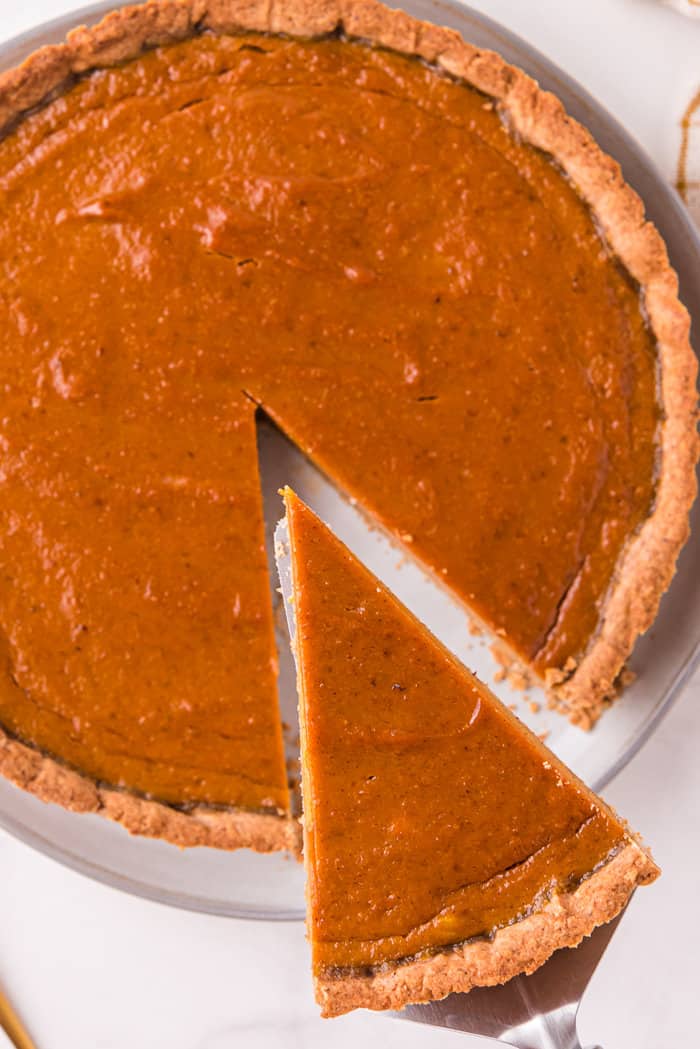 Pumpkin tart with a slice being taken out.