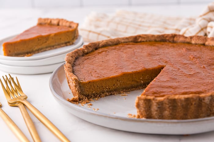 Pumpkin tart with a slice cut out of it.