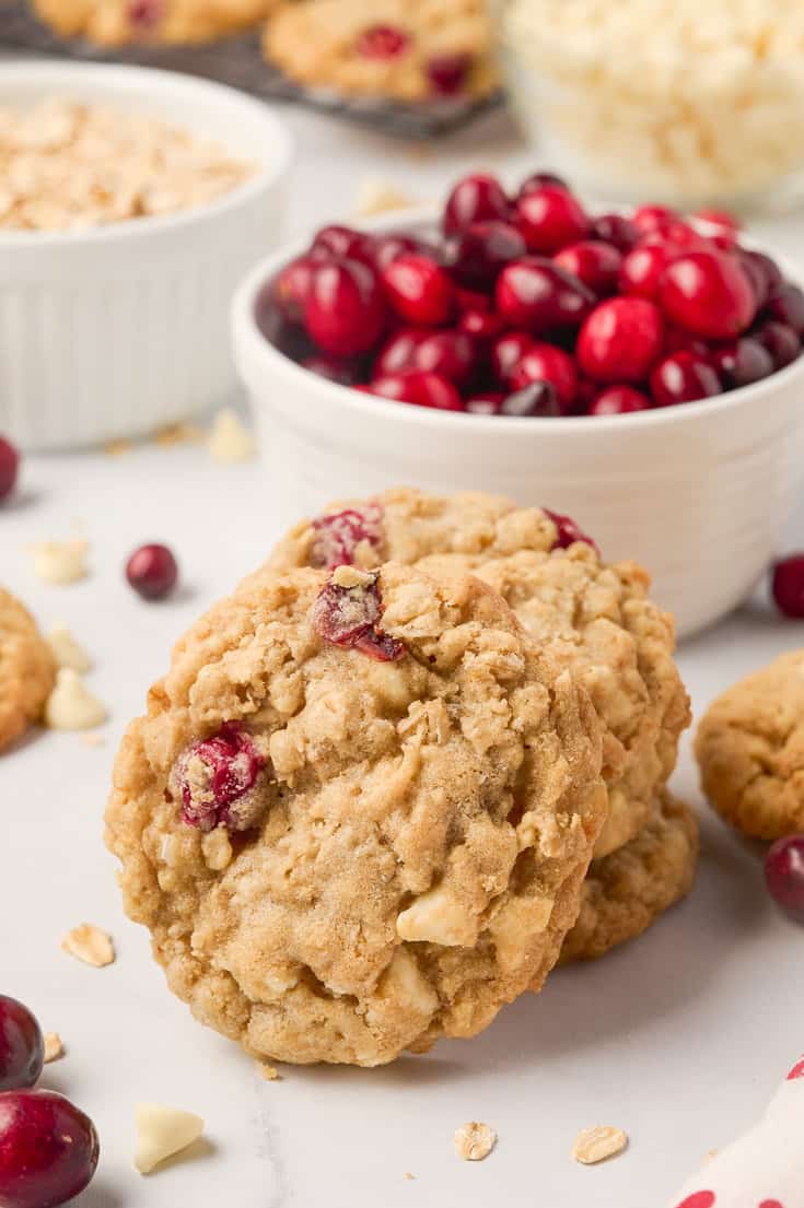 oatmeal cookies stacked with bowl of cranberries in background