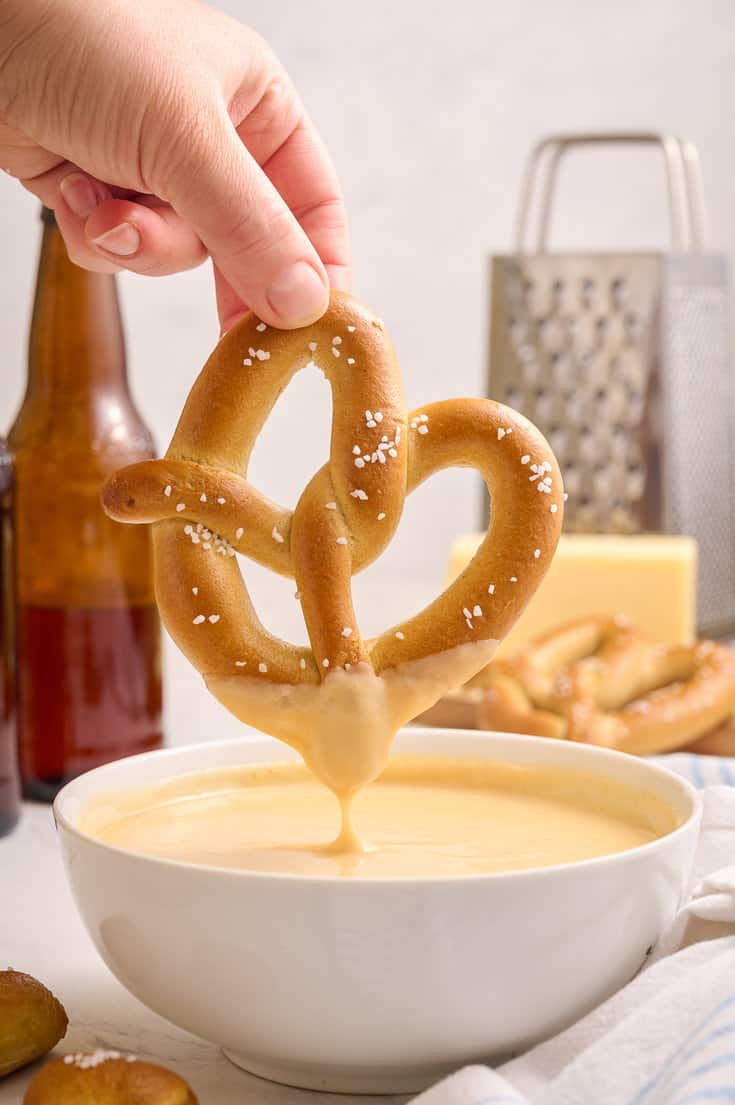 Beer cheddar cheese dip with a pretzel dipped into it.