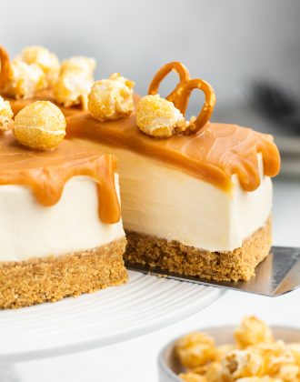 No bake caramel cheesecake on a cake stand with a slice being removed.