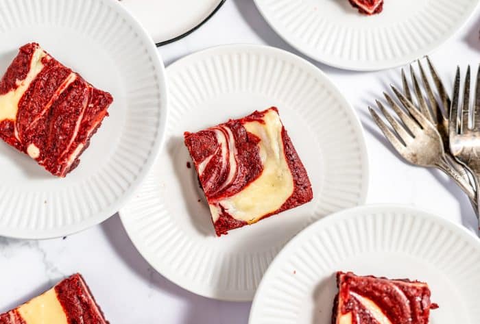 Red velvet cheesecake brownies on a white plates.