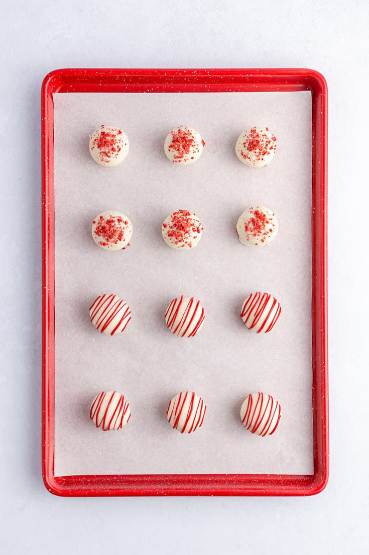 Strawberry cake balls being covered in white melting chocolate.