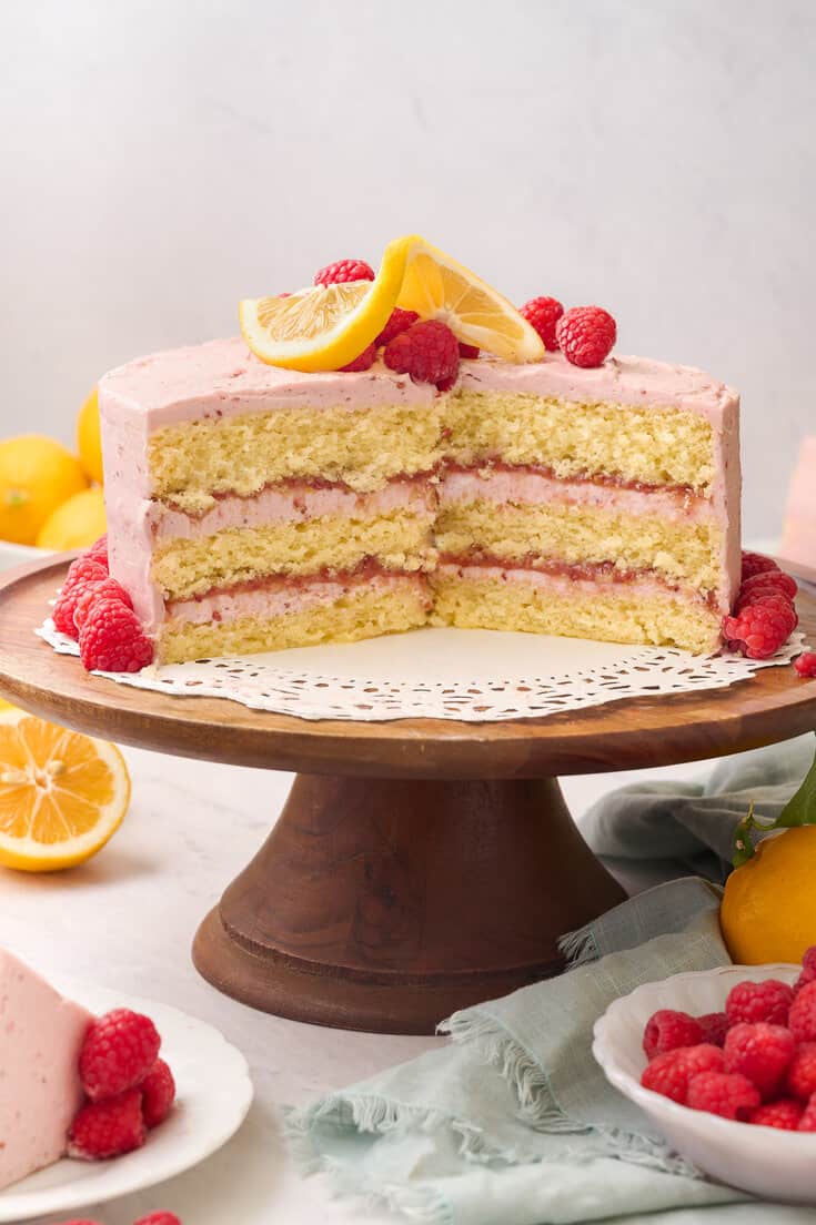 Lemon raspberry cake cut open on a cake stand.