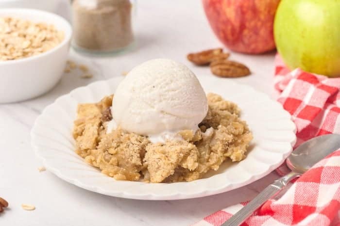 A plate of apple crisp with cardamom with a scoop of ice cream.
