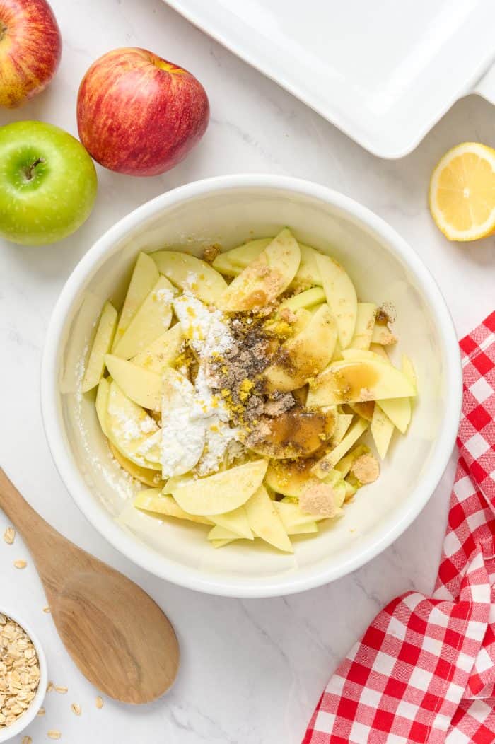 Sliced apples mixed with spices in a white bowl.