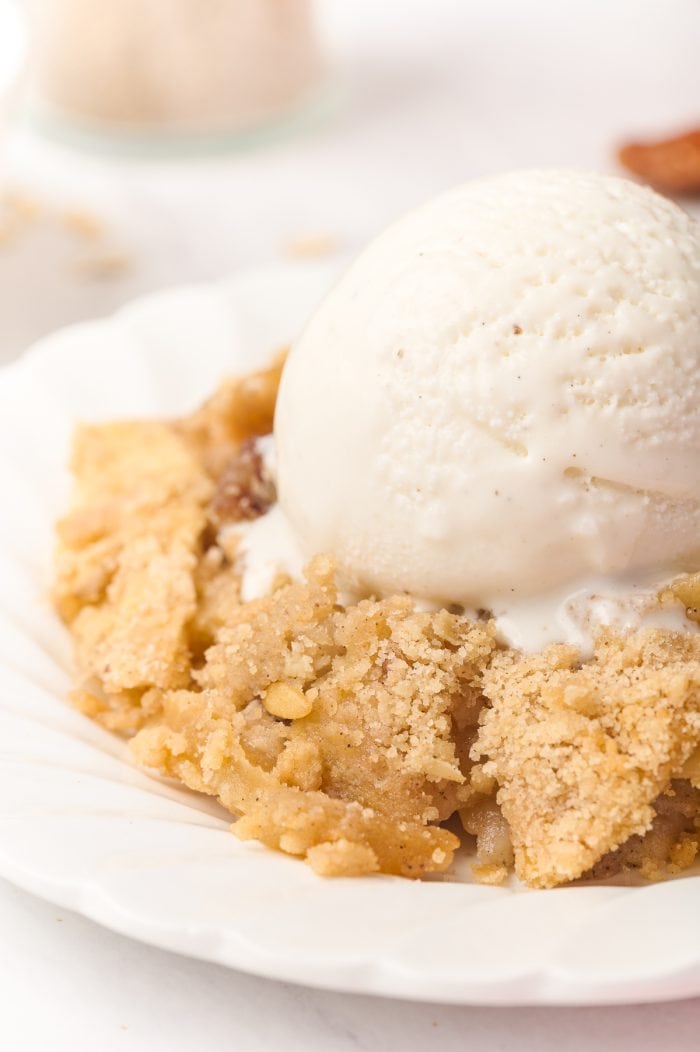 A plate of apple crisp with a scoop of ice cream.