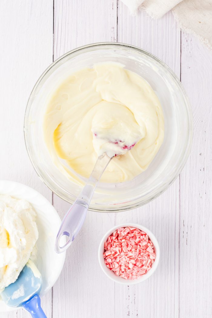 Cream cheese mixed with white chocolate in a glass bowl.