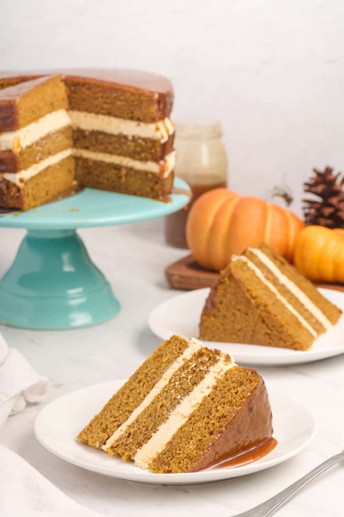 Two slices of Naked Pumpkin Cake with the whole cake in the background.