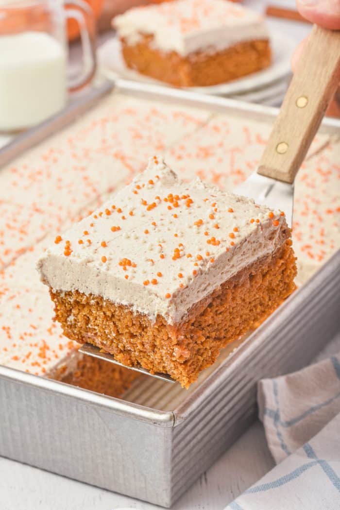 A slice of pumpkin cake being removed from the cake pan.