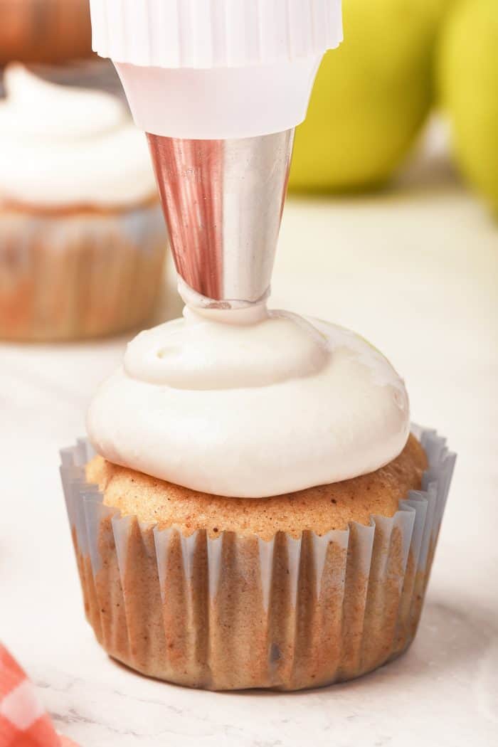 Piping marshmallow frosting onto cupcakes.