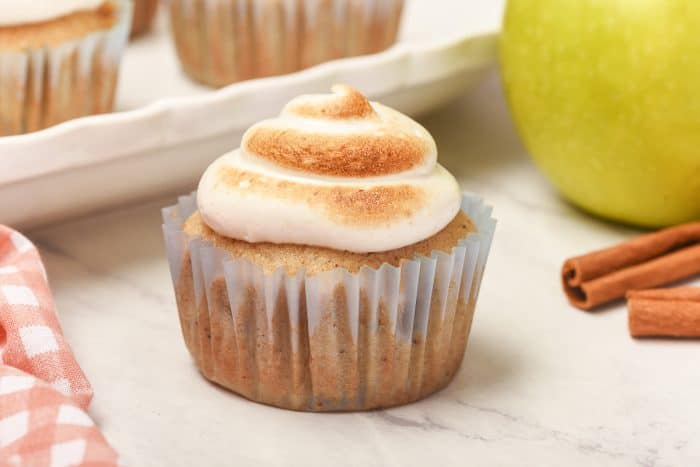 A spiced apple cupcakes with a tray of cupcakes behind it.