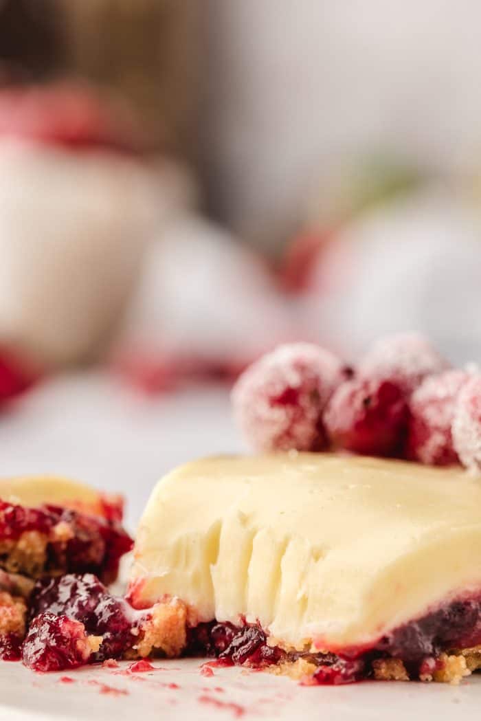 A closeup of a slice of white chocolate cranberry tart on a white plate.