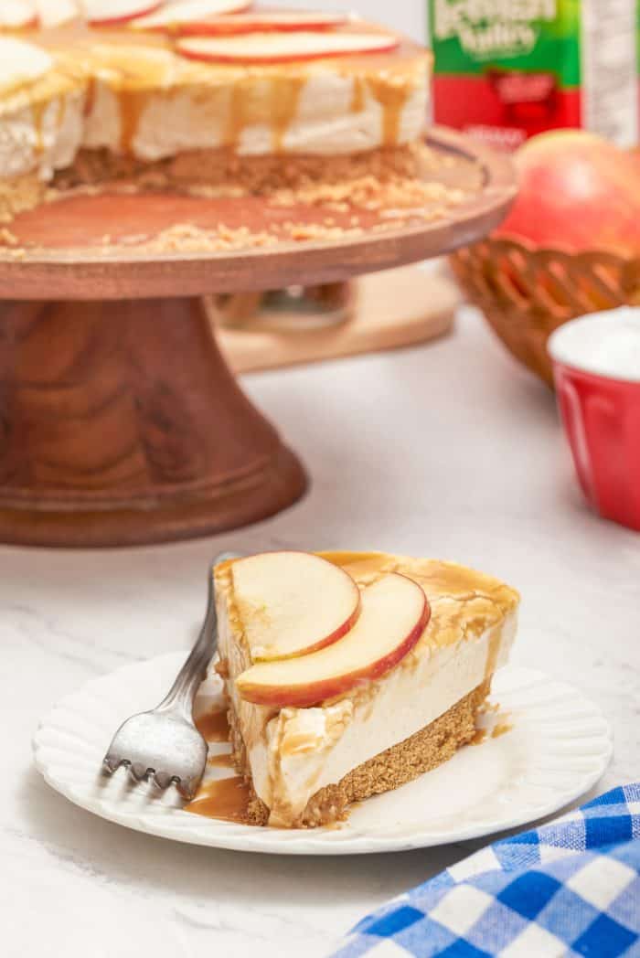 A slice of apple caramel cheesecake on a plate with a fork.