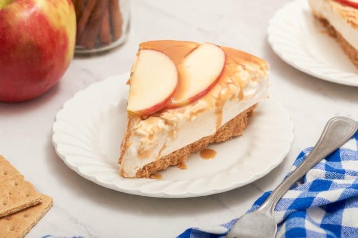 A closeup of a slice of apple cheesecake on a white plate.