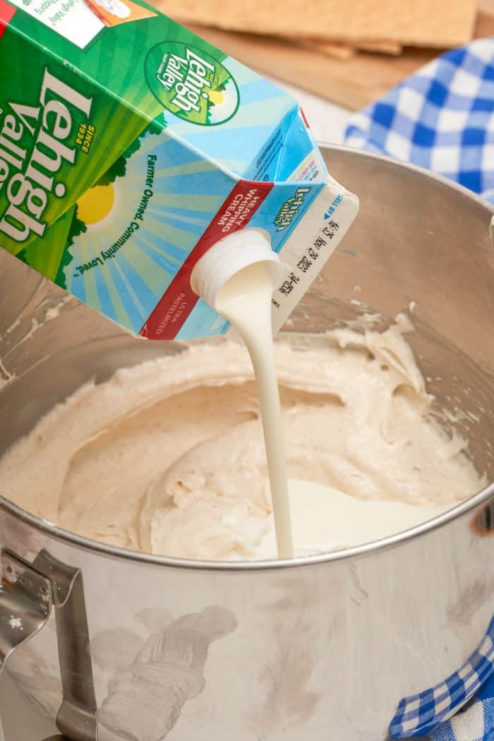 Heavy cream being added to a bowl of cream cheese.