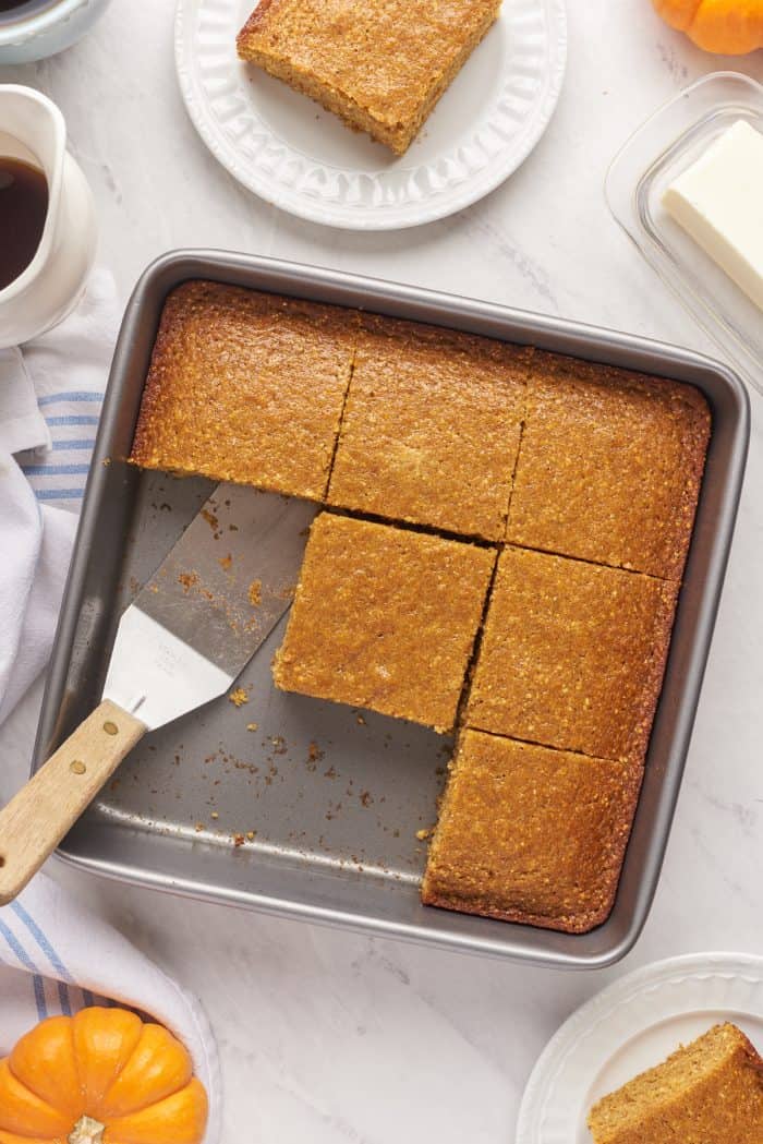 A baking pan filled with slices of pumpkin cornbread with a few slices removed.