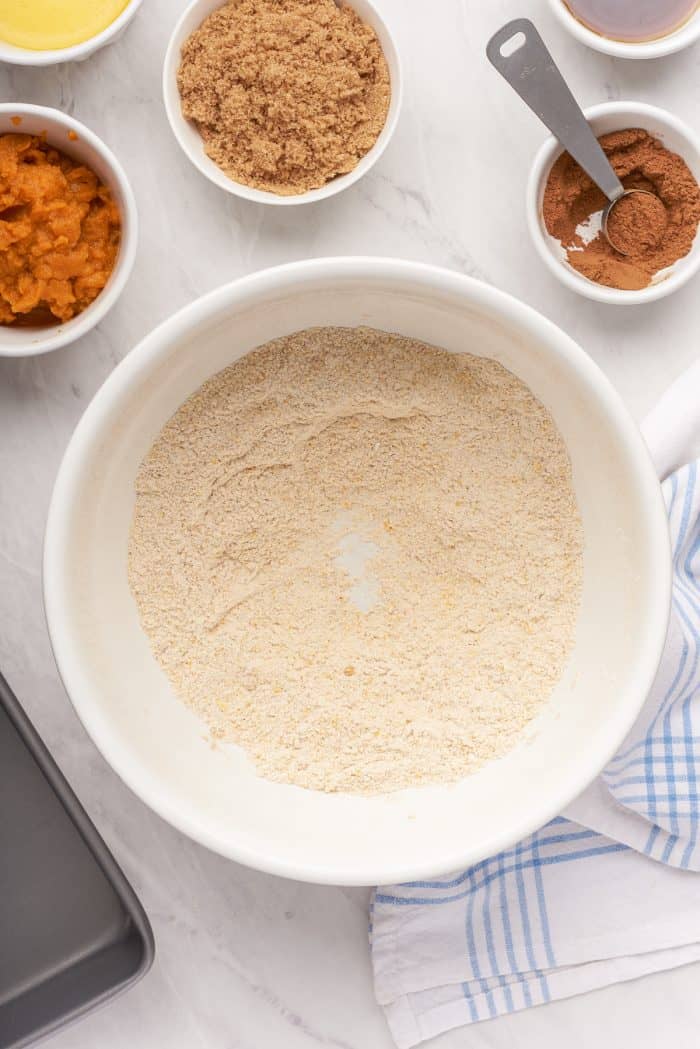 A bowl with flour, cornmeal, and pumpkin spice mixed together.