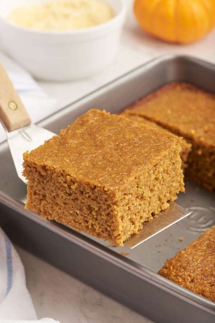 A slice of pumpkin cornbread being lifted from the baking pan.