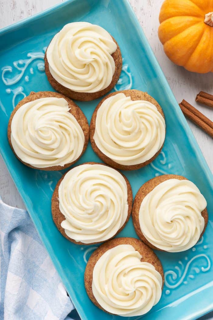 A blue plate with six pumpkin snickerdoodles with cream cheese frosting.