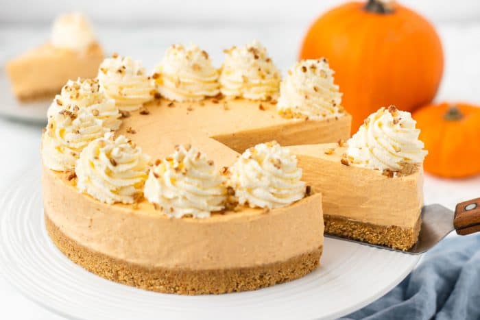 An image of a no bake pumpkin cheesecake with a slice being removed.