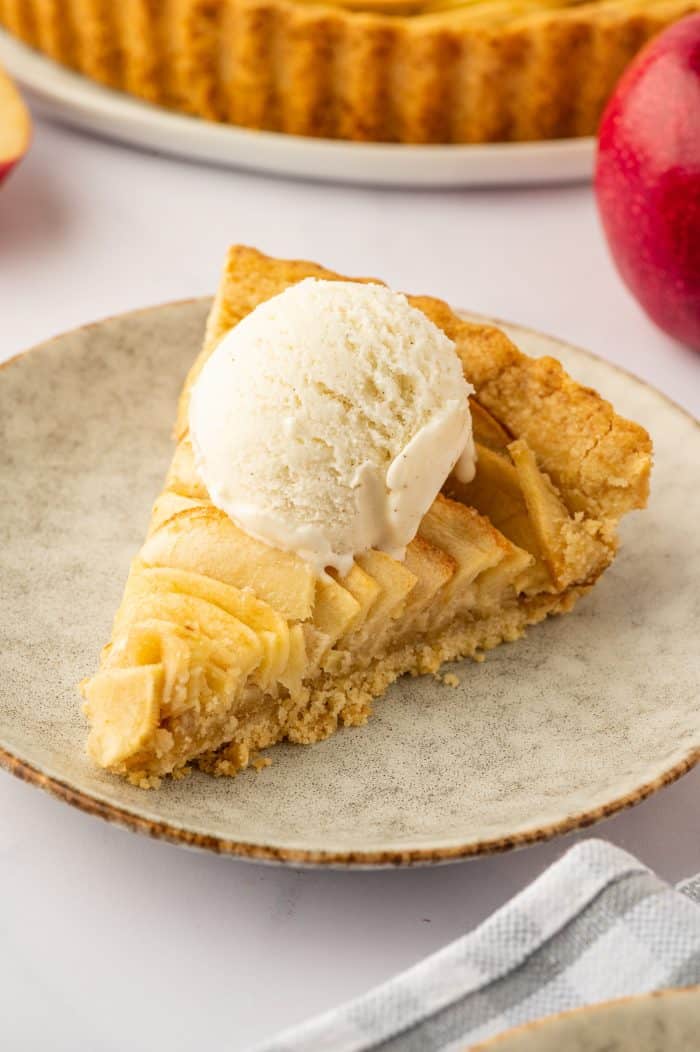 A slice of apple tart with a scoop of vanilla ice cream.